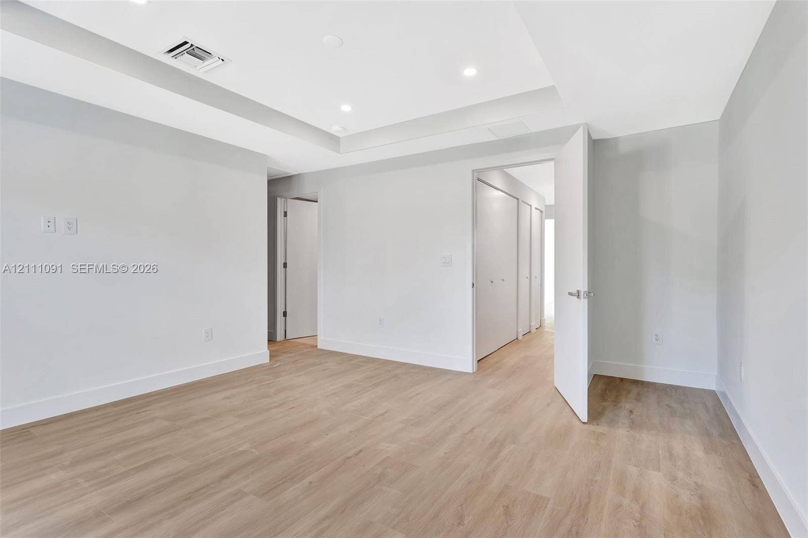 Room featuring recessed lighting, tray ceiling, wood-finish flooring, and built-in closet storage