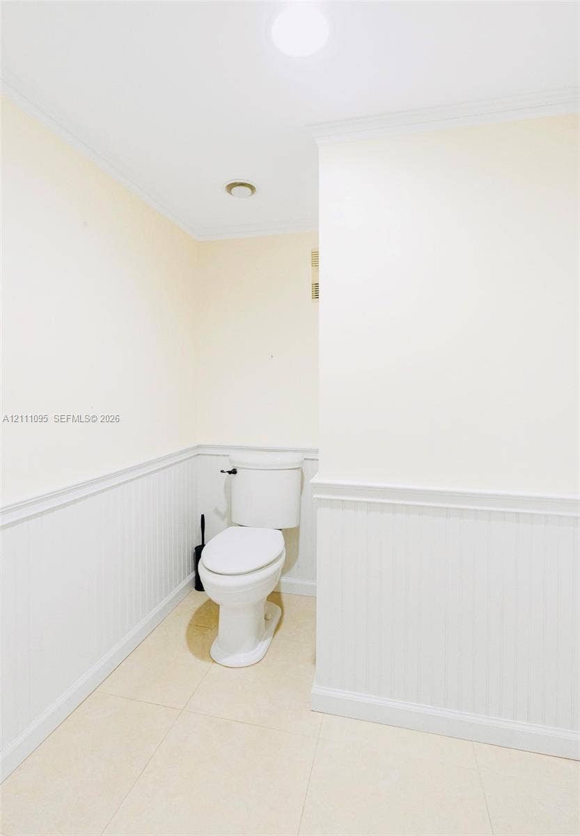 120 SW 96th Terrace, #104, Plantation, FL 33324 White beadboard wainscoting with chair rail molding, neutral tile flooring, and a porcelain toilet