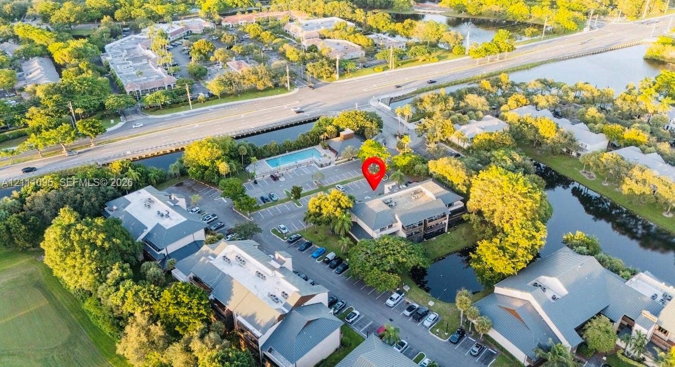 120 SW 96th Terrace, #104, Plantation, FL 33324 Aerial perspective featuring a multi-story building, an outdoor swimming pool, paved parking areas, and surrounding waterways