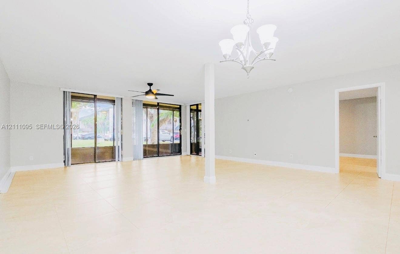 120 SW 96th Terrace, #104, Plantation, FL 33324 Large format tile flooring, multi-panel sliding glass doors, overhead ceiling fan with light fixture, and decorative multi-arm chandelier