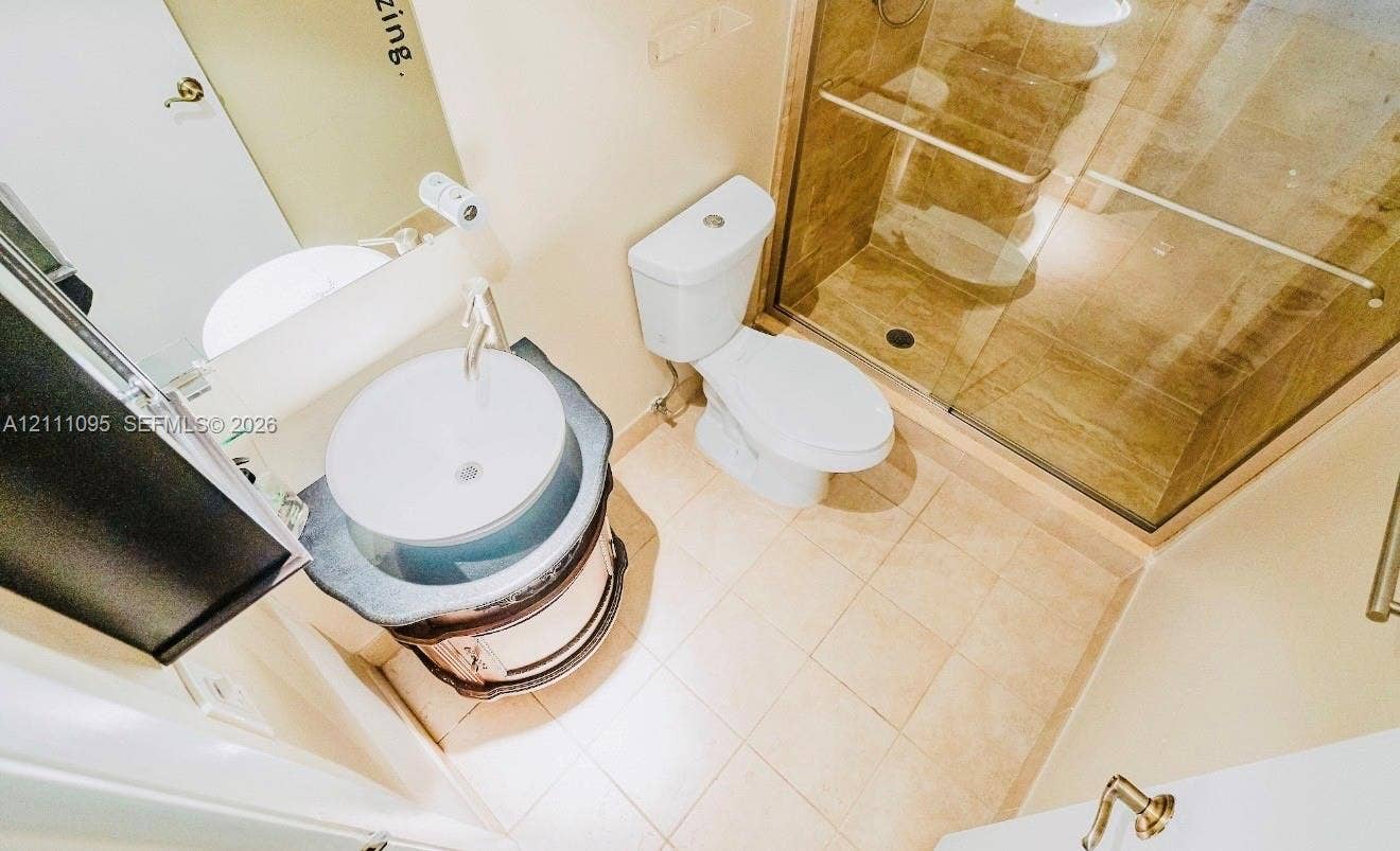 120 SW 96th Terrace, #104, Plantation, FL 33324 Bathroom featuring a vanity with a stone countertop and circular vessel sink, tiled flooring, and a glass-enclosed shower with tiled walls