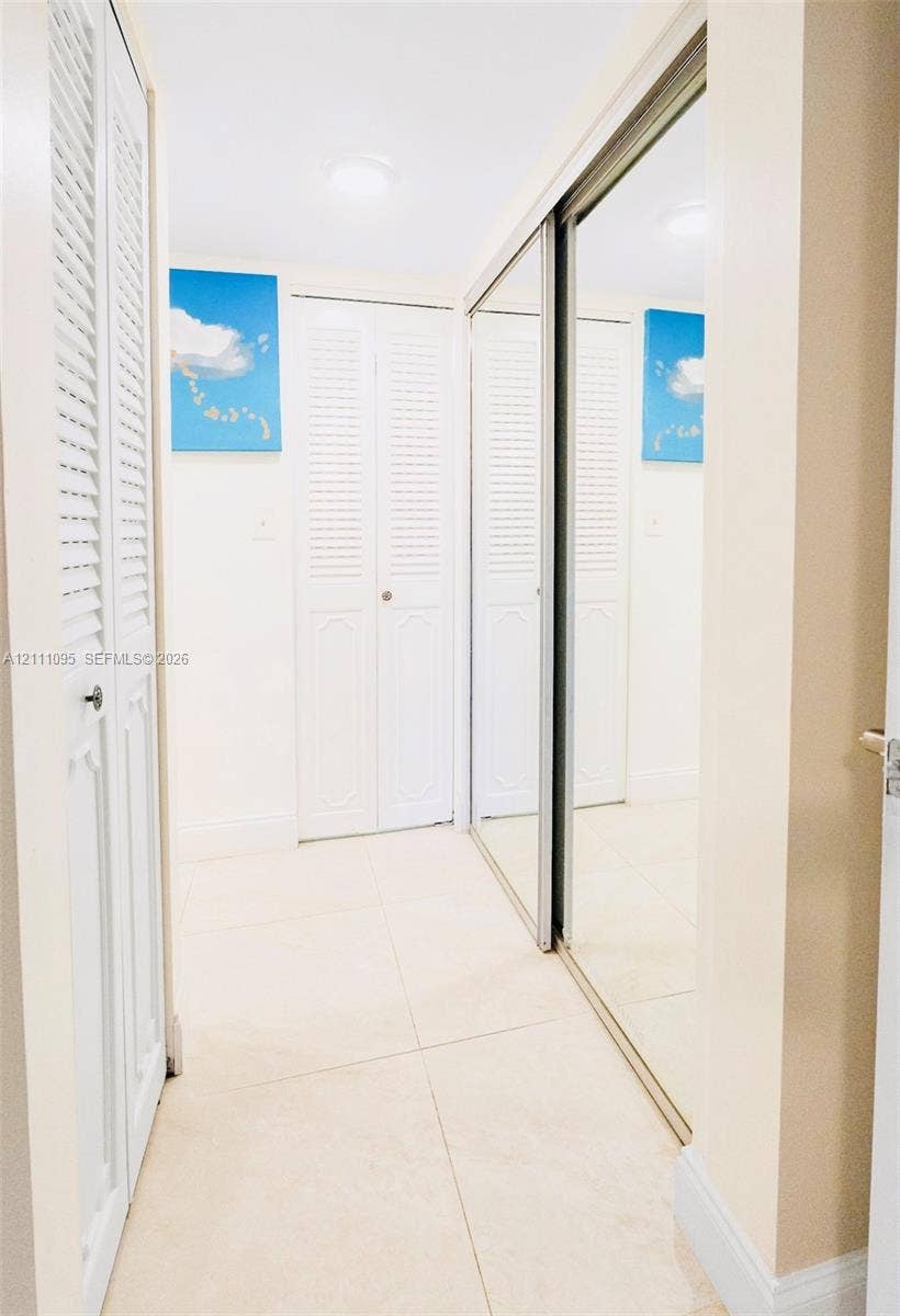 120 SW 96th Terrace, #104, Plantation, FL 33324 Large-format tile flooring, dual mirrored sliding closet doors, and white louvered bifold doors