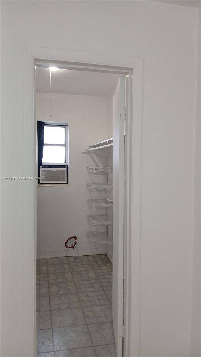 325 NE 2nd Street, #4, Hallandale Beach, Hallandale Beach, FL 33009 Storage room featuring tile flooring, a window, integrated wall shelving, and a hanging rod