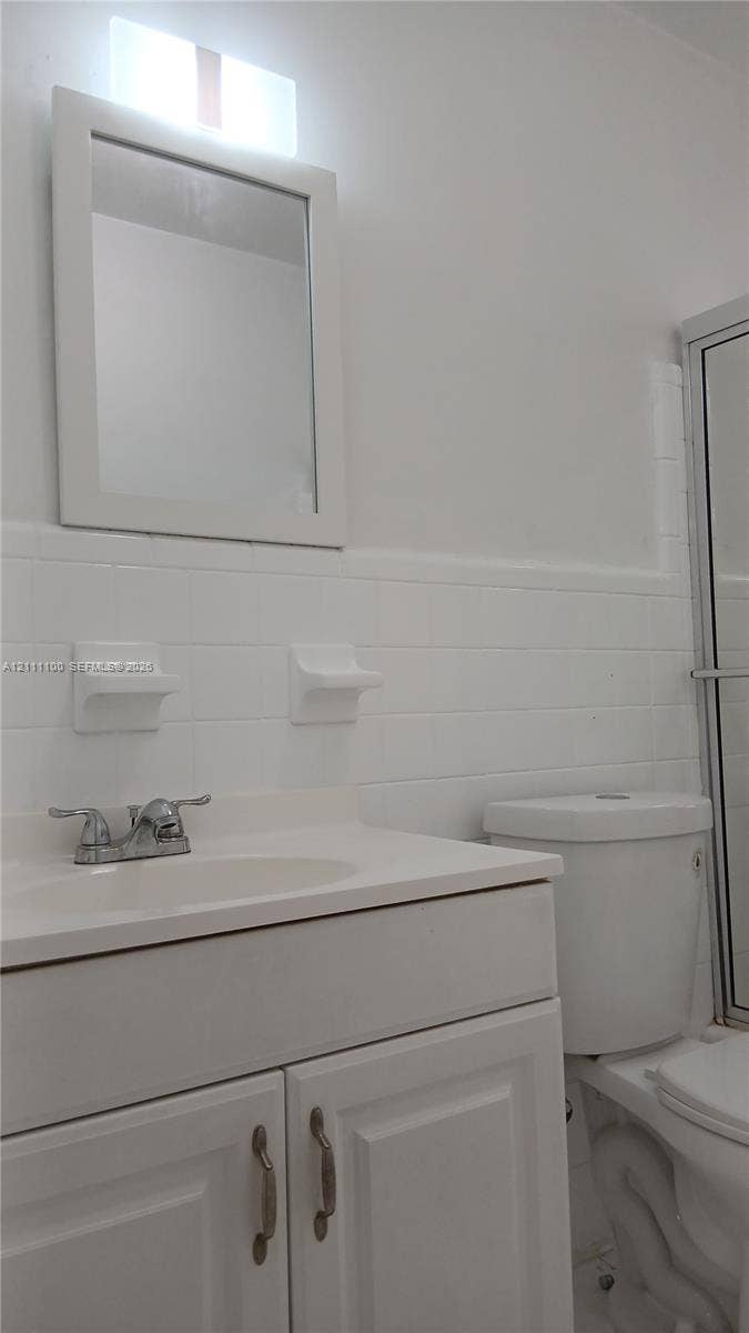325 NE 2nd Street, #4, Hallandale Beach, Hallandale Beach, FL 33009 Bathroom vanity with a white cabinet, integrated sink, metal faucet, and wall-mounted mirror, featuring white subway tile wall surround