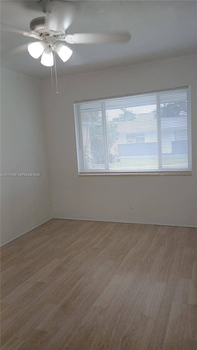 325 NE 2nd Street, #4, Hallandale Beach, Hallandale Beach, FL 33009 Interior space featuring light-toned wood-finish flooring, a ceiling fan with integrated lighting, and a large multi-pane window