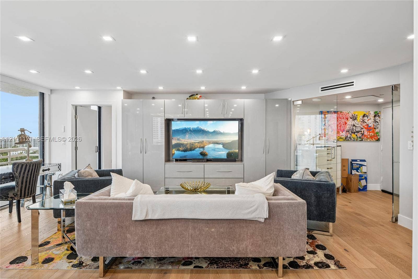 3300 NE 192nd Street, #1813, Aventura, FL 33180 Living area featuring engineered wood-finish flooring, recessed ceiling lighting, built-in floor-to-ceiling high-gloss cabinetry, and a glass-enclosed partitioned space