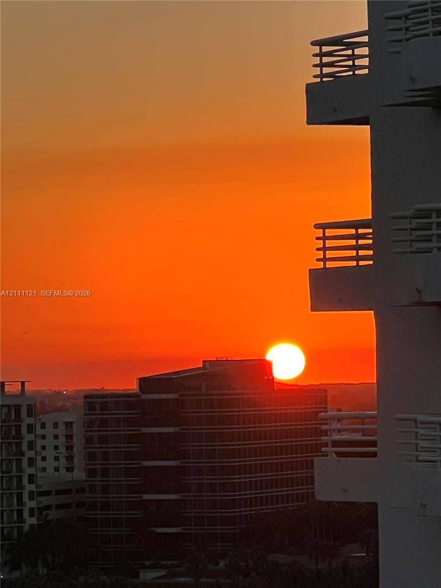 3300 NE 192nd Street, #1813, Aventura, FL 33180 Elevated balconies with horizontal railings featuring a sunset backdrop