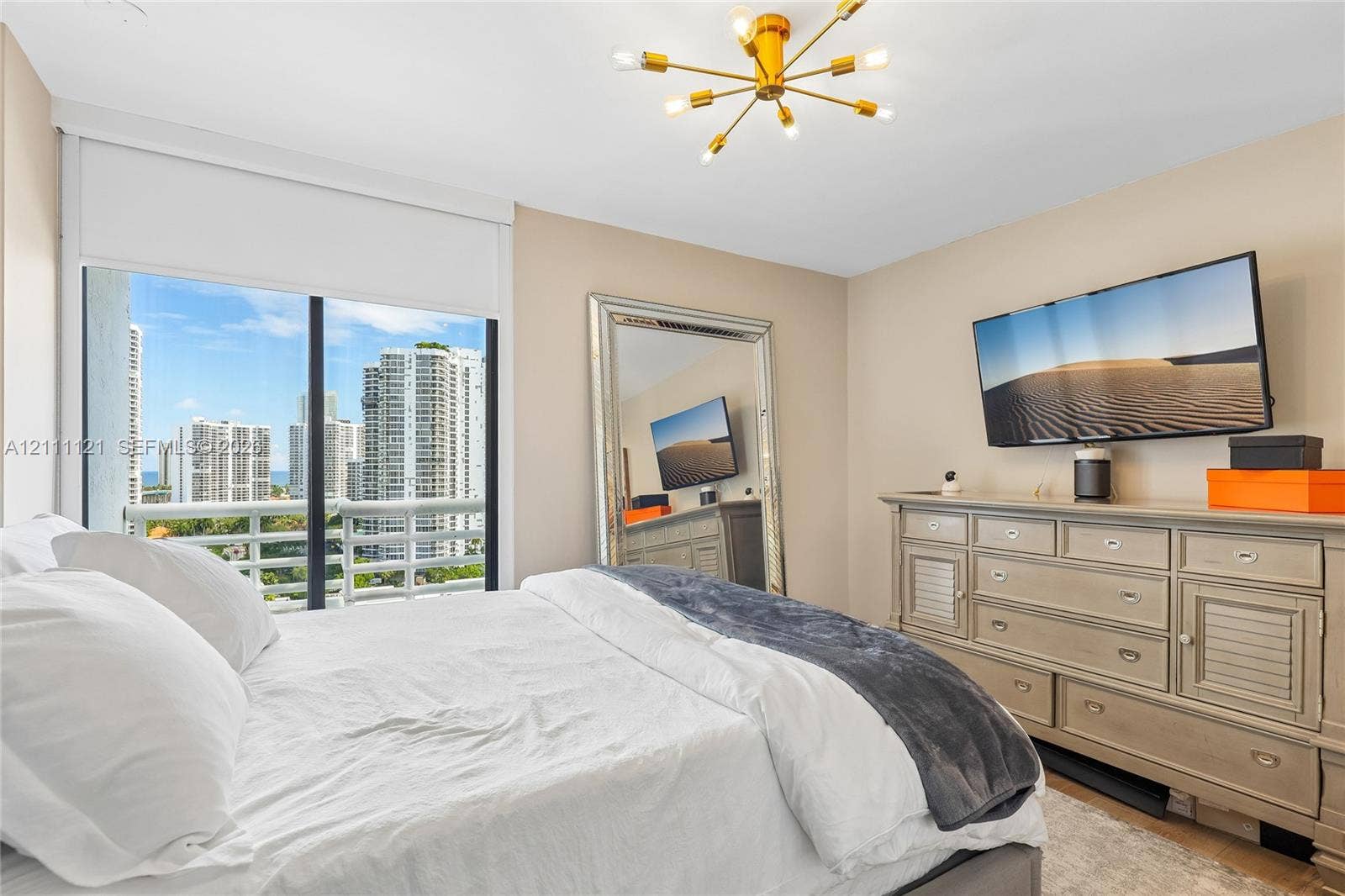 3300 NE 192nd Street, #1813, Aventura, FL 33180 Floor-to-ceiling sliding glass door, private balcony, brass-finish multi-arm light fixture, and neutral wall palette