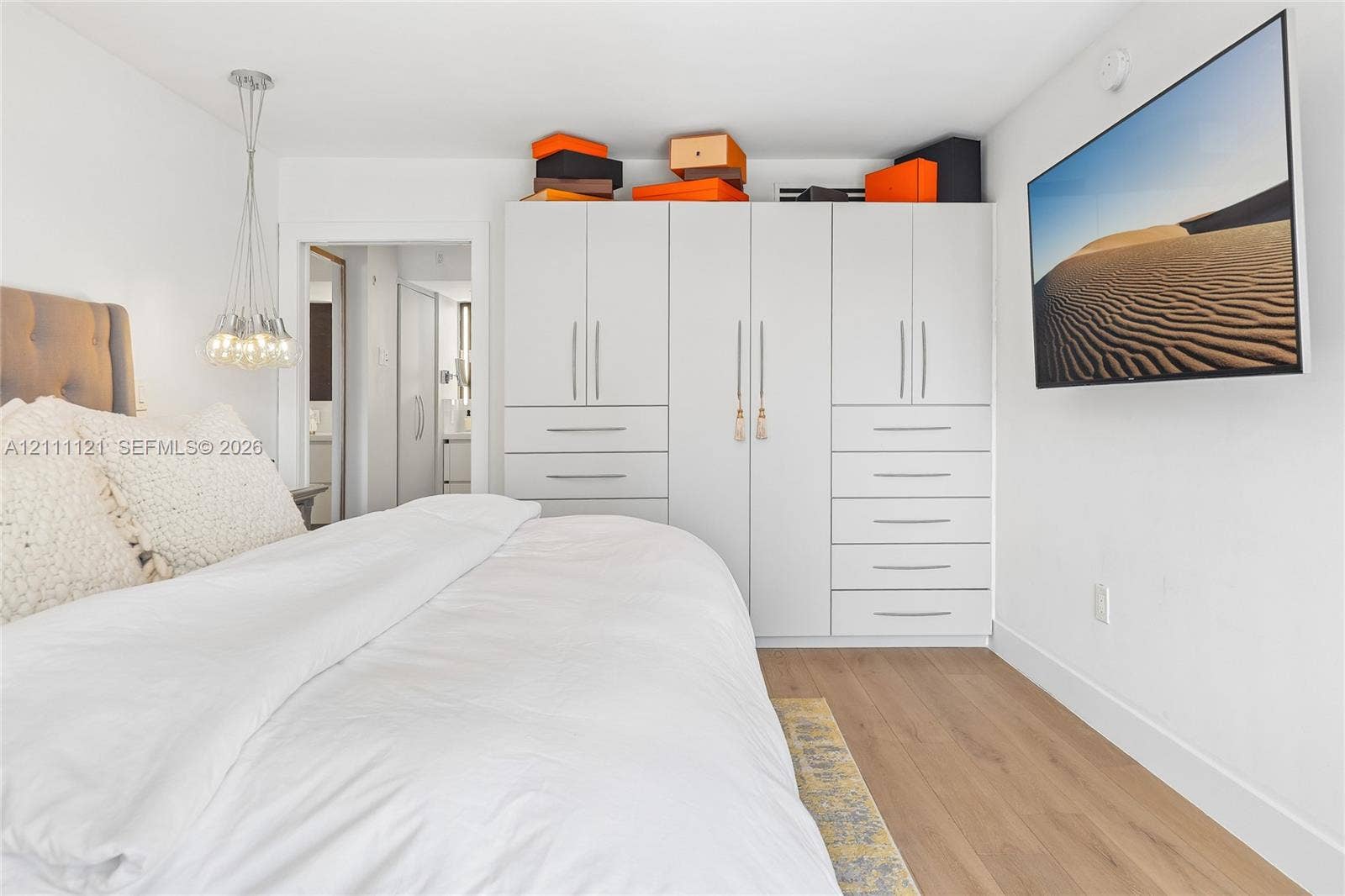 3300 NE 192nd Street, #1813, Aventura, FL 33180 Built-in white floor-to-ceiling wardrobe with integrated drawers, wood-finish flooring, and a multi-bulb suspended pendant light fixture