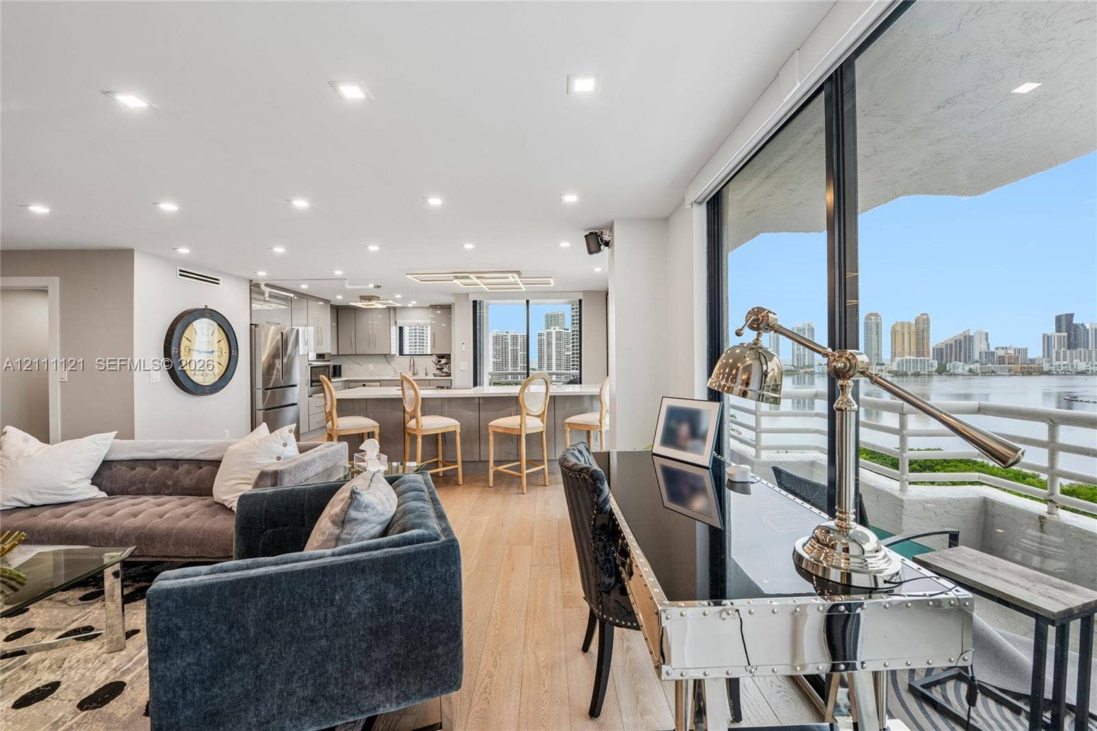 3300 NE 192nd Street, #1813, Aventura, FL 33180 Open-concept interior featuring light-toned wood-finish flooring, recessed lighting, kitchen with stainless steel appliances and island, and expansive floor-to-ceiling glass wall