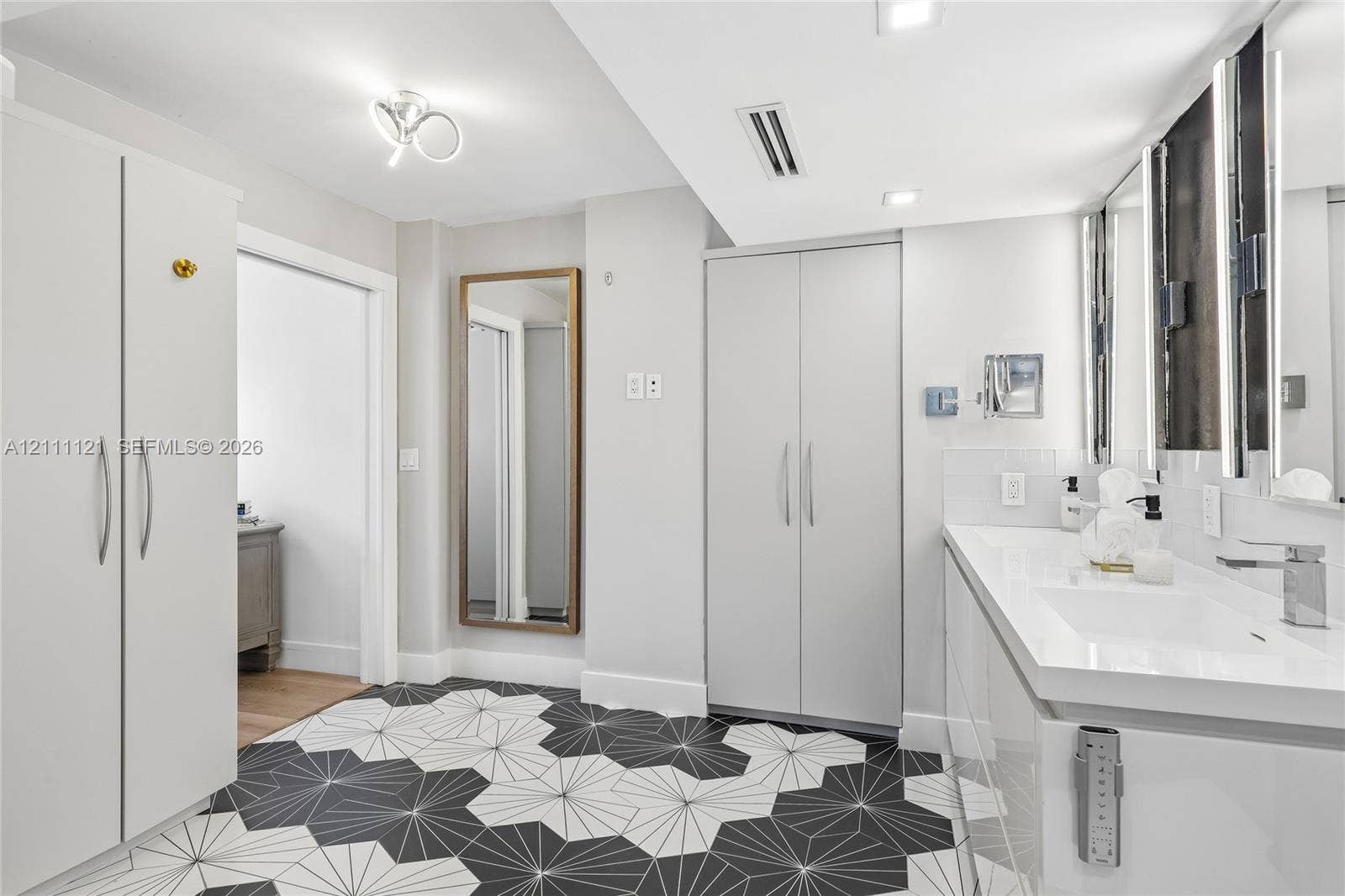 3300 NE 192nd Street, #1813, Aventura, FL 33180 Bathroom featuring a white dual-sink vanity with an integrated countertop, geometric tile flooring, floor-to-ceiling white cabinetry, and recessed lighting