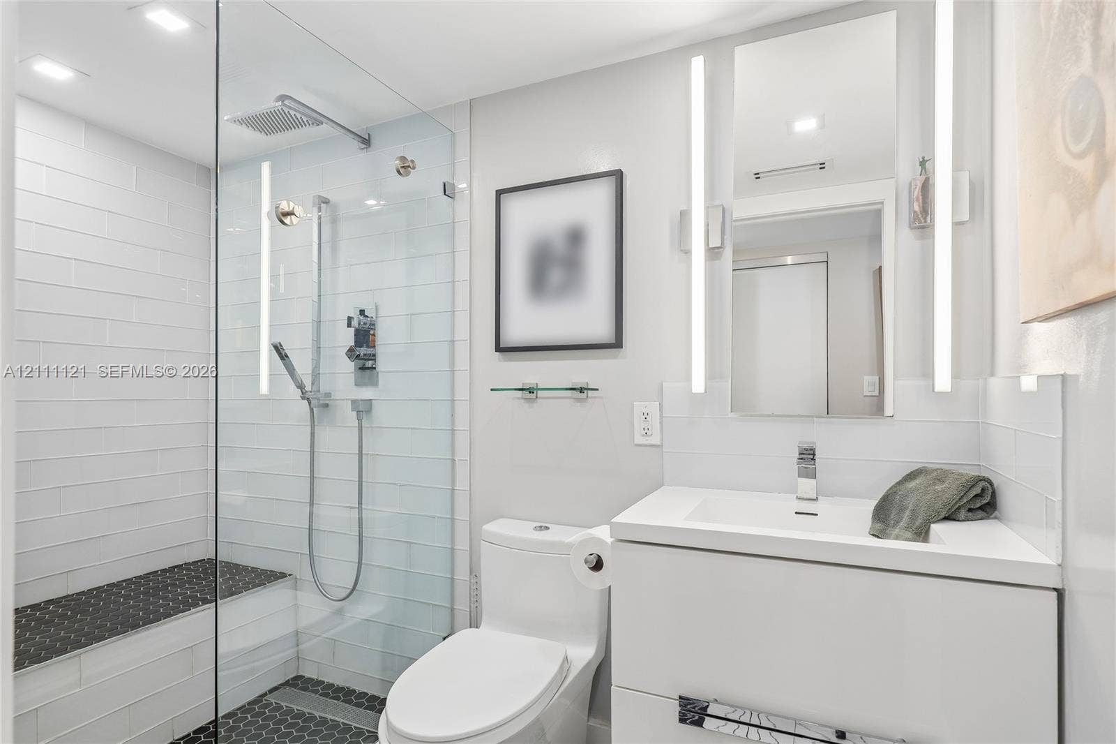3300 NE 192nd Street, #1813, Aventura, FL 33180 Walk-in shower with glass enclosure, integrated tile bench, dual-function showerhead, floating white vanity, and vertical LED-integrated vanity lighting