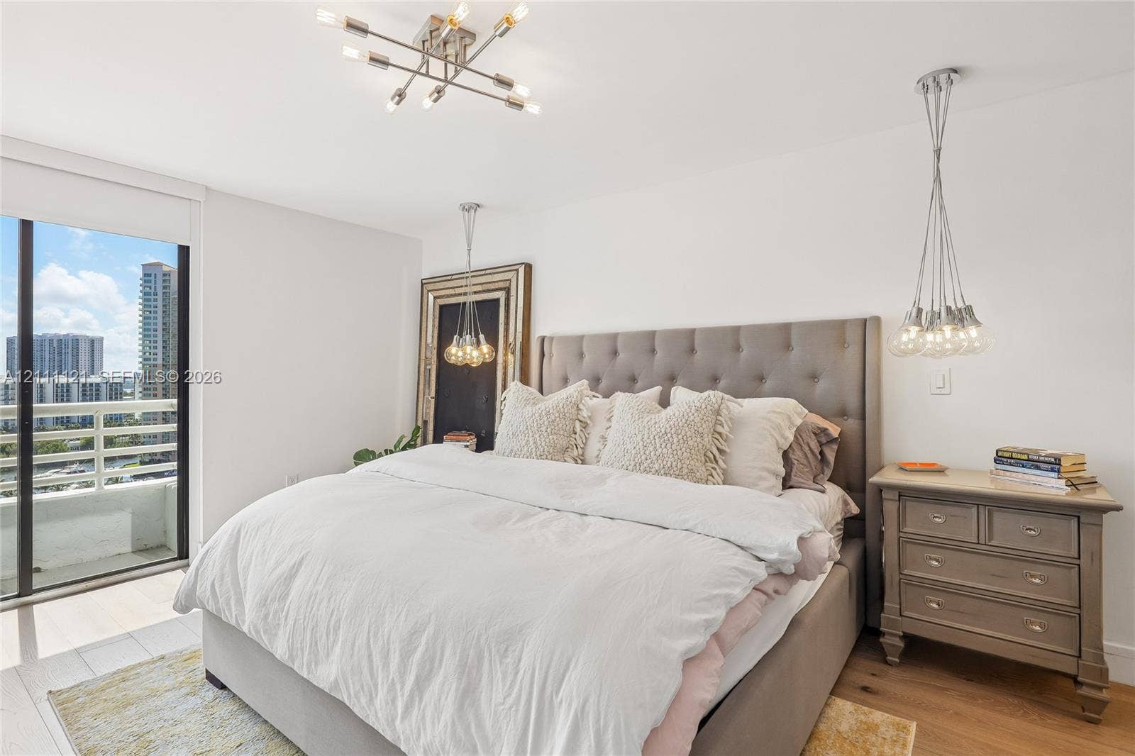 3300 NE 192nd Street, #1813, Aventura, FL 33180 Multi-light modern chandelier, adjustable pendant lighting, wood-finish flooring, sliding glass door, and balcony