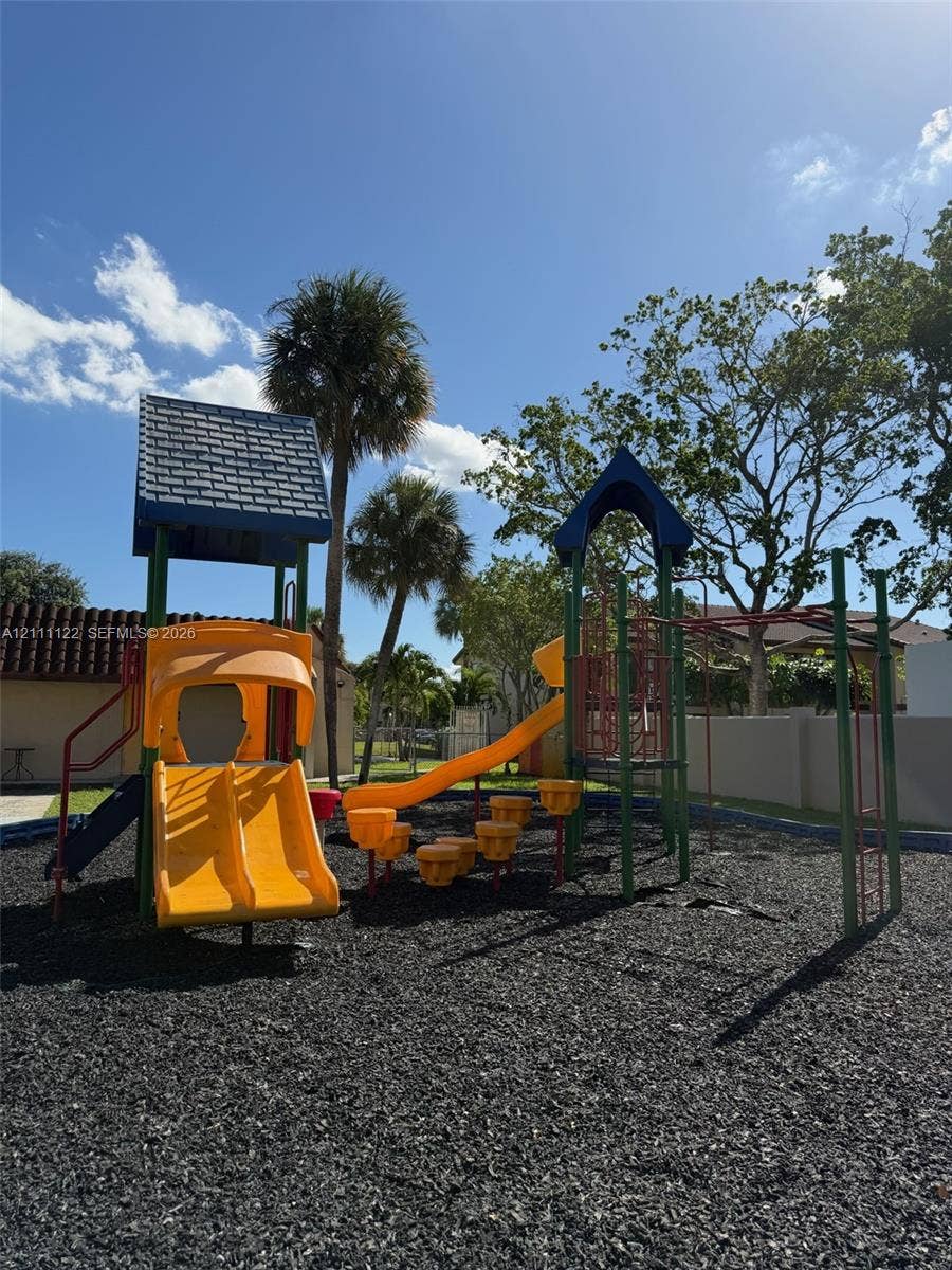 Outdoor recreational area featuring a multi-level climbing structure, dual slides, stepping platforms, and rubberized ground cover