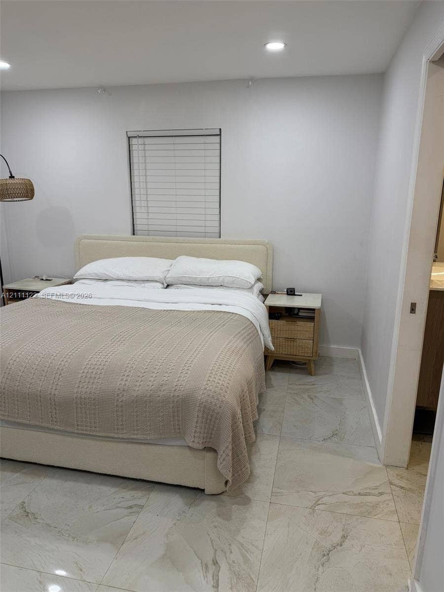 Large-format light-toned tile flooring, recessed ceiling lighting, and a window with horizontal blinds