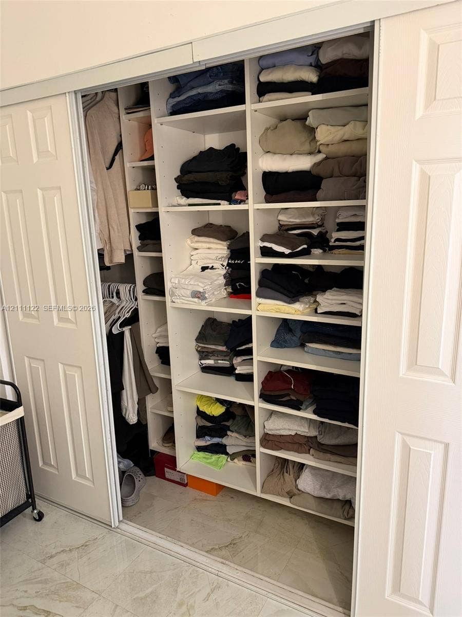 Custom built-in closet featuring white paneled sliding doors, floor-to-ceiling adjustable shelving, and integrated clothing rods