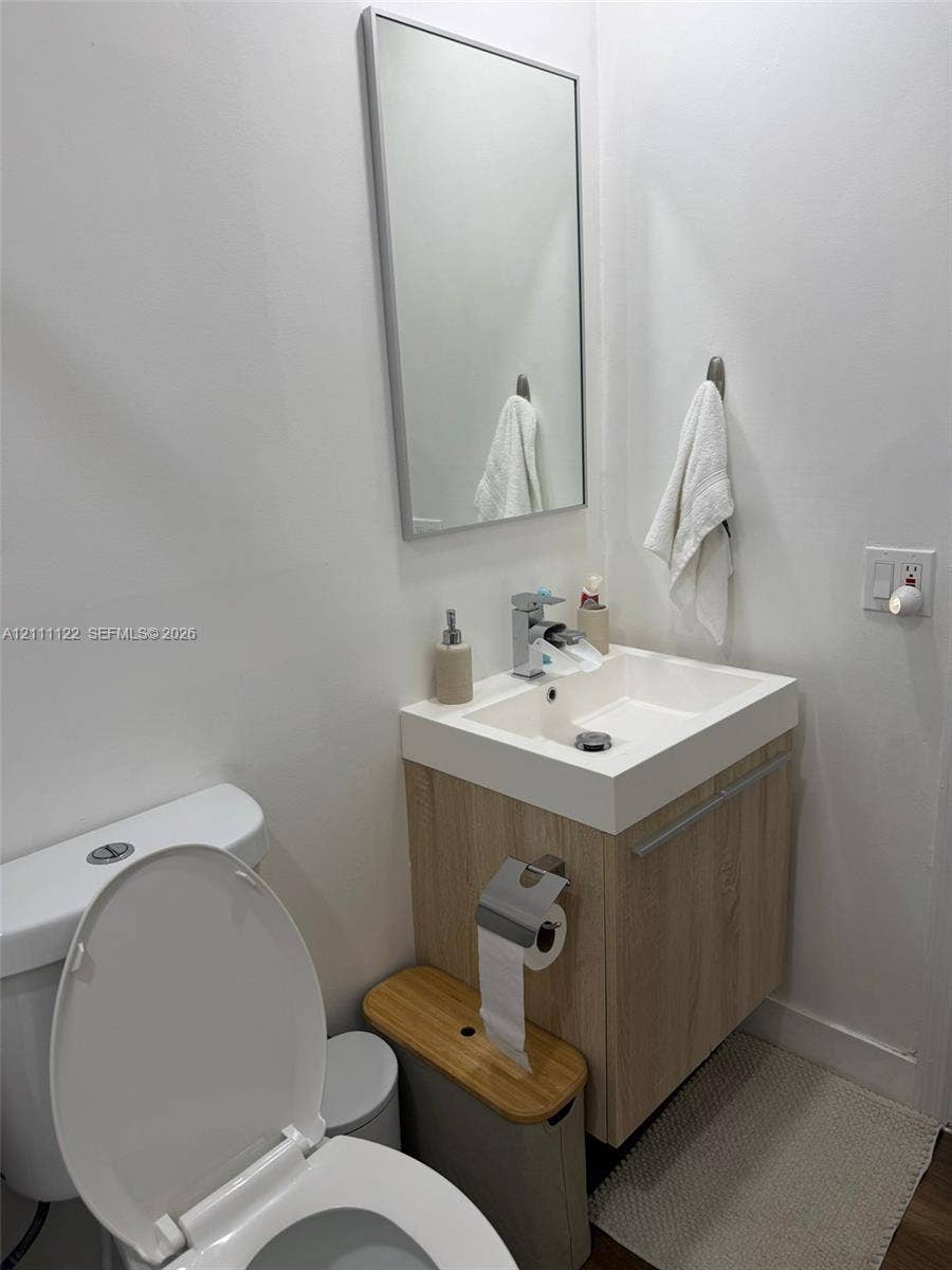 Floating vanity with wood-finish cabinetry, rectangular vessel sink, wall-mounted mirror, and chrome single-handle faucet