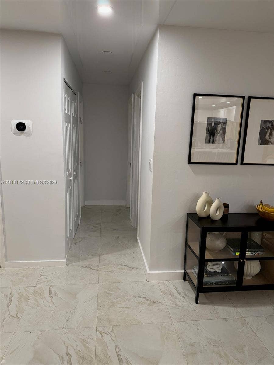 Large-format tile flooring, recessed ceiling lighting, and smart thermostat interface
