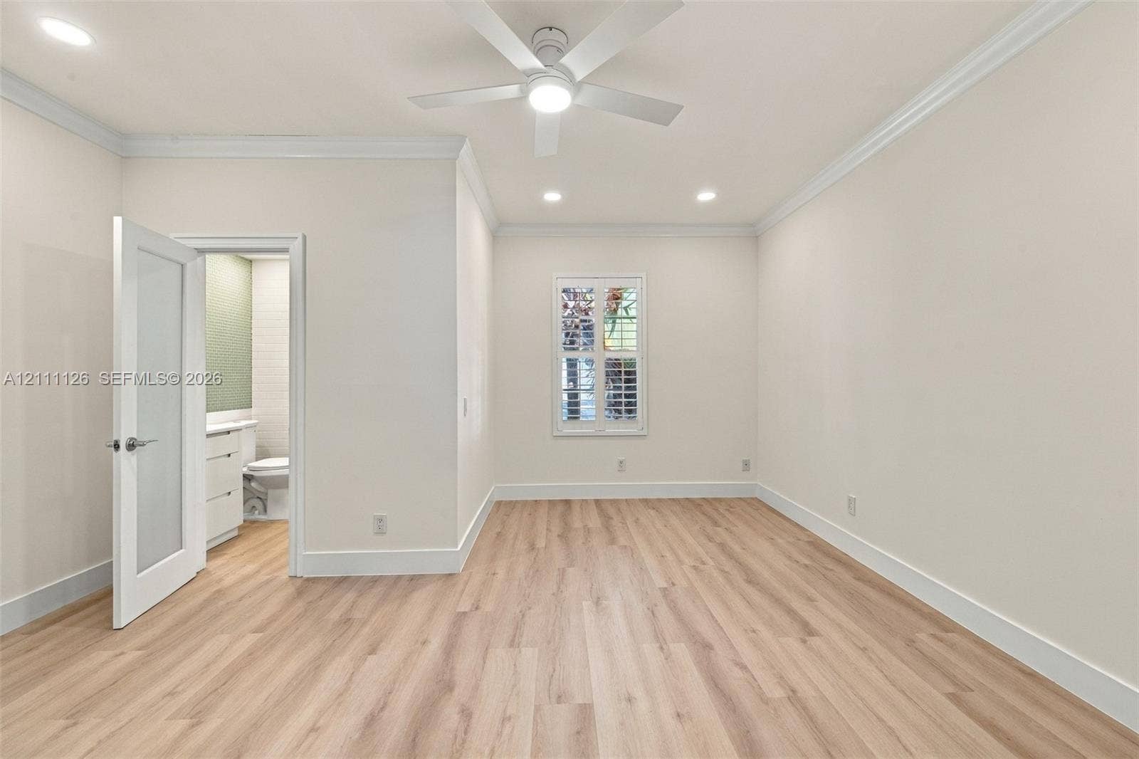 Interior space featuring wood-finish flooring, recessed lighting, crown molding, a modern ceiling fan with integrated lighting, and a single-panel interior door with glass insert
