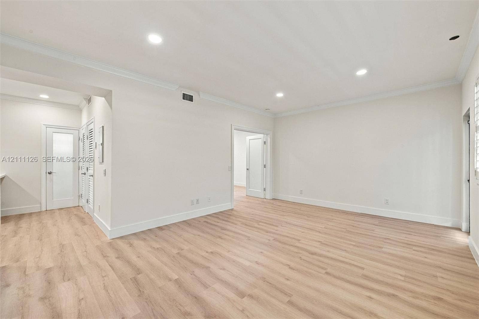 Spacious room featuring wood-finish flooring, recessed lighting, crown molding, and neutral wall color