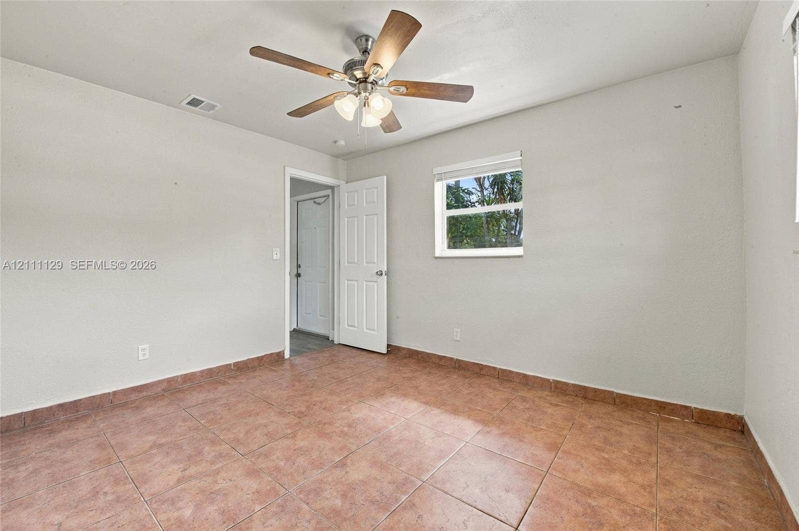 Interior room featuring oversized ceramic tile flooring, a multi-blade ceiling fan with integrated light fixture, a six-panel door, and a single-hung window