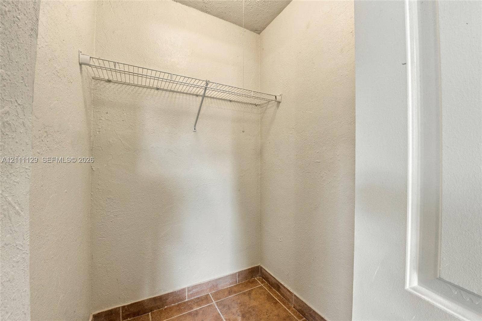 Storage area featuring neutral-toned textured wall finishes, tile flooring, and integrated wire shelving