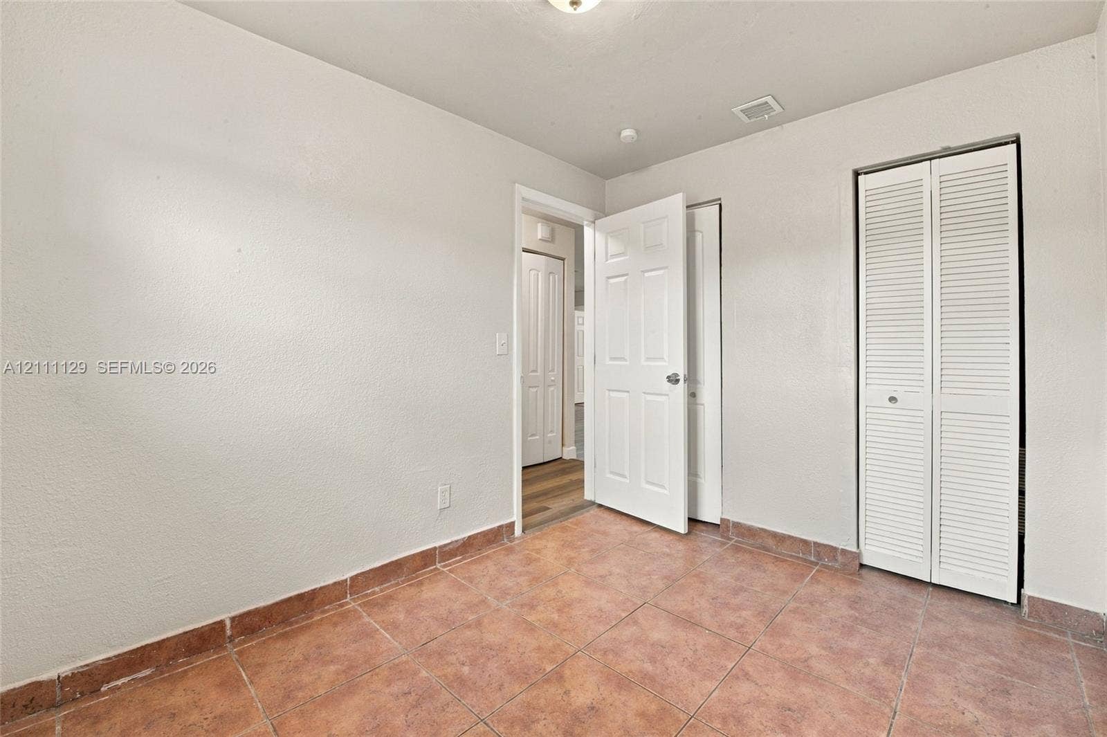 Room featuring tile flooring, neutral wall paint, and a bi-fold louvered closet door