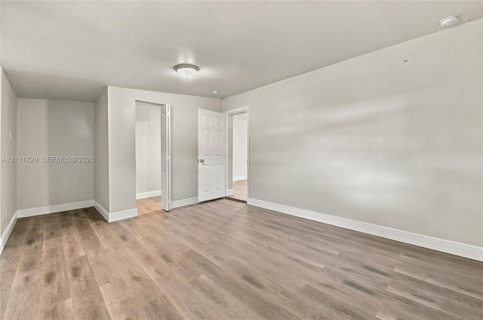 Interior space featuring wood-finish flooring, neutral wall paint, and a flush-mount ceiling light fixture