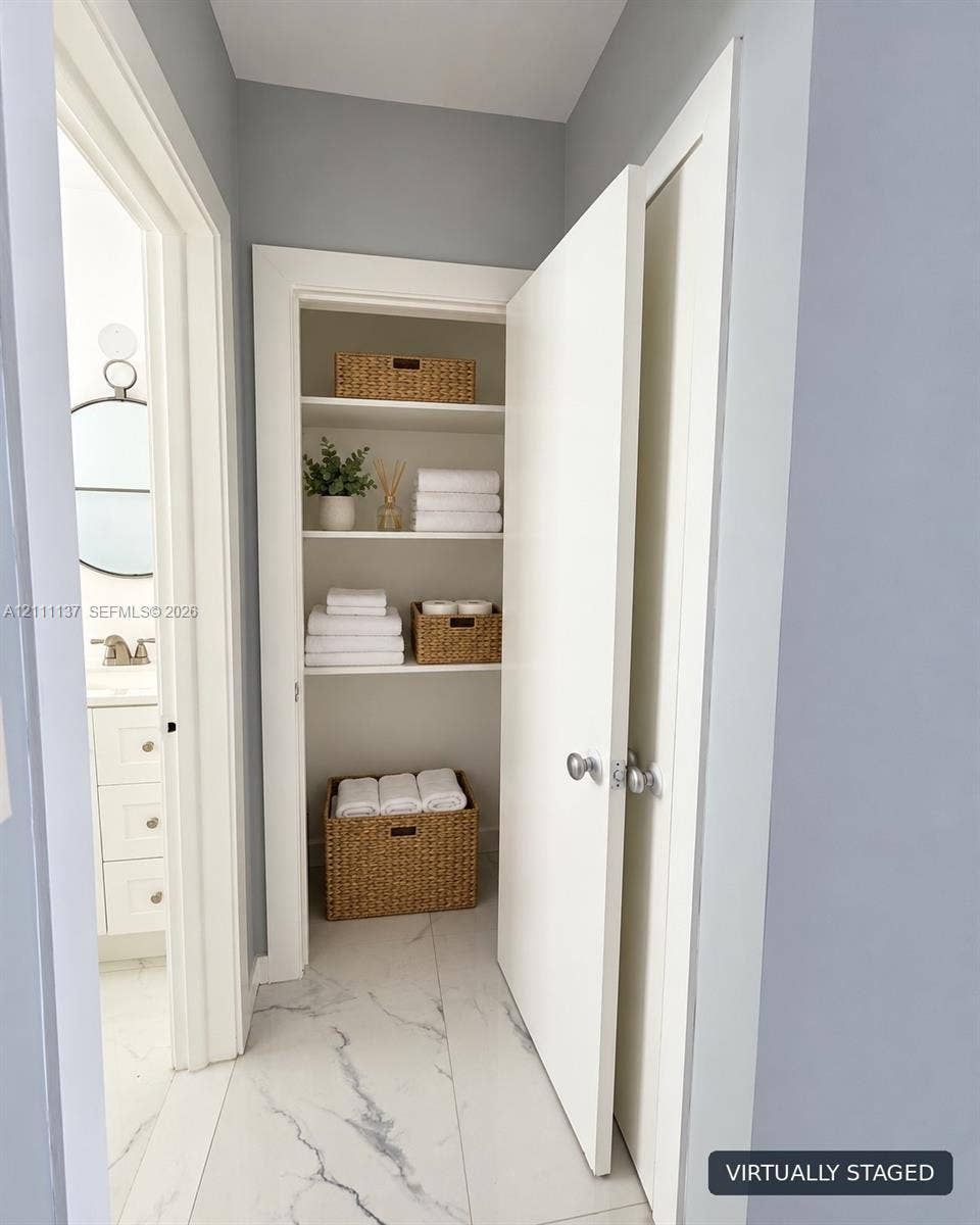 635 8th Street, #205, Miami Beach, Miami Beach, FL 33139 Built-in storage closet featuring multi-level shelving and white interior casing, complemented by large-format light-toned stone-finish tile flooring