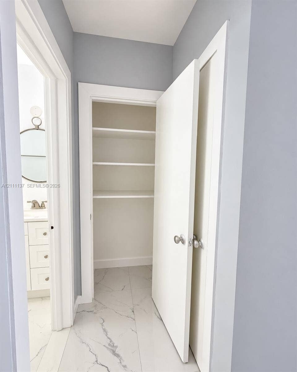 635 8th Street, #205, Miami Beach, Miami Beach, FL 33139 Storage closet featuring white shelving, paired with large-format light-toned flooring featuring grey veining