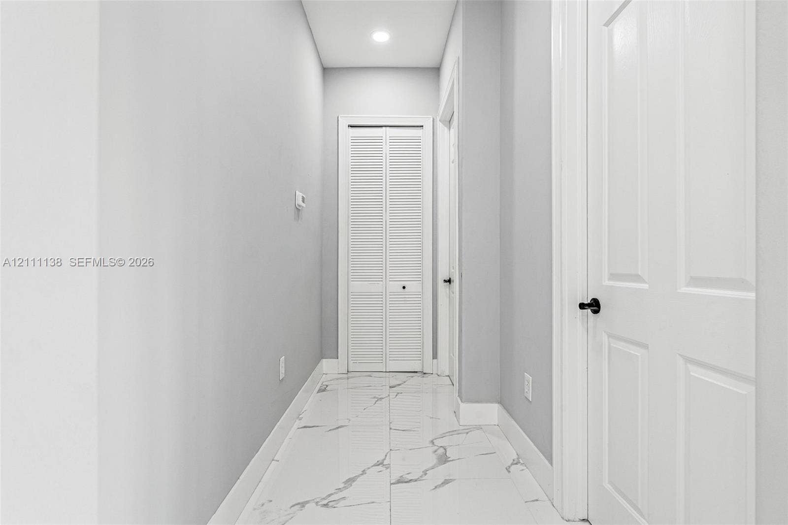 19363 SW 79th Avenue, Cutler Bay, FL 33157 Hallway featuring polished tile flooring with a veined pattern, recessed ceiling lighting, and crisp white interior doors with matte black hardware