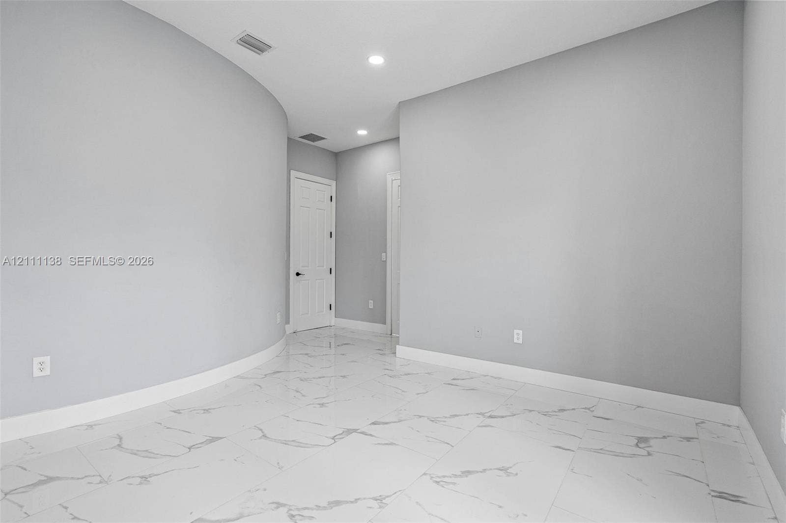 19363 SW 79th Avenue, Cutler Bay, FL 33157 Interior space featuring polished large-format tile flooring with veining, curved wall architecture, and recessed ceiling lighting