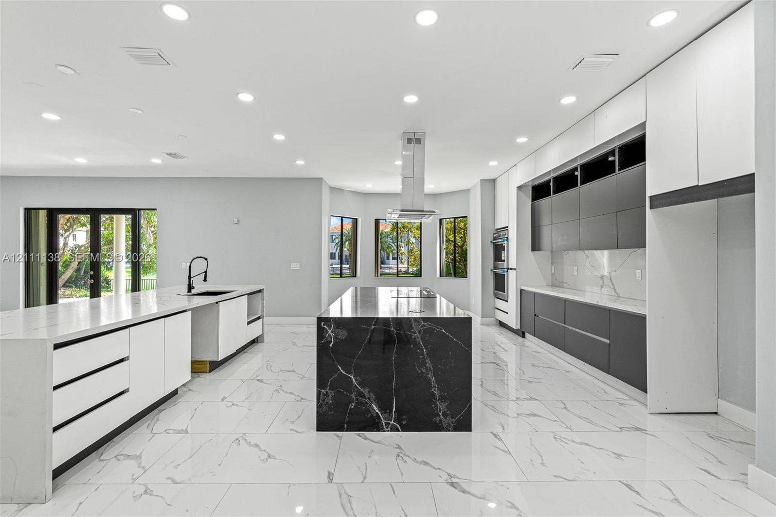 19363 SW 79th Avenue, Cutler Bay, FL 33157 Modern kitchen featuring flat-panel cabinetry, a central island with a contrasting stone finish, stone-surface countertops, tile flooring, and a stainless steel ceiling-mounted vent hood