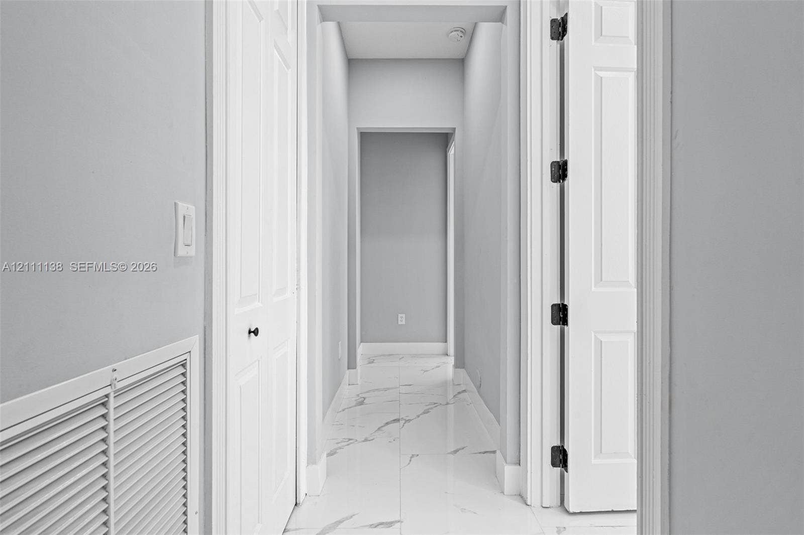 19363 SW 79th Avenue, Cutler Bay, FL 33157 Hallway featuring white veined tile flooring, solid core two-panel doors, and neutral wall tones