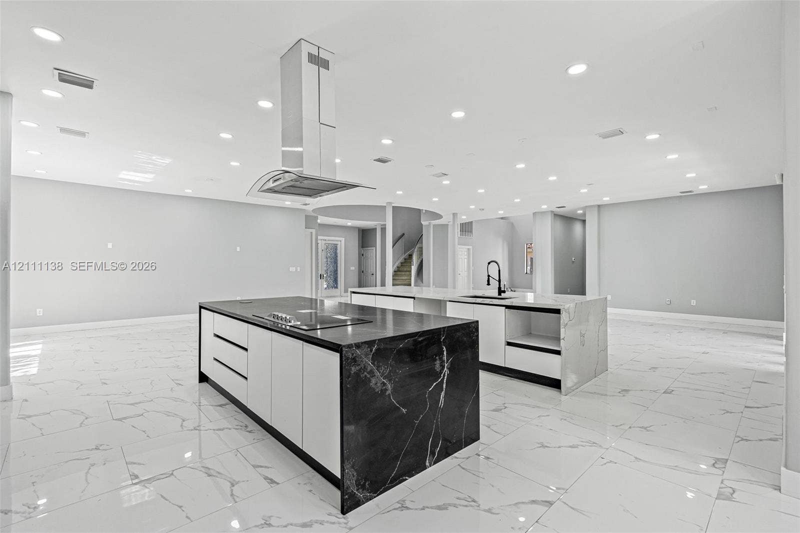 19363 SW 79th Avenue, Cutler Bay, FL 33157 Dual kitchen islands featuring stone-finish waterfall countertops, flat-panel cabinetry, a stainless steel chimney-style range hood, and porcelain tile flooring throughout