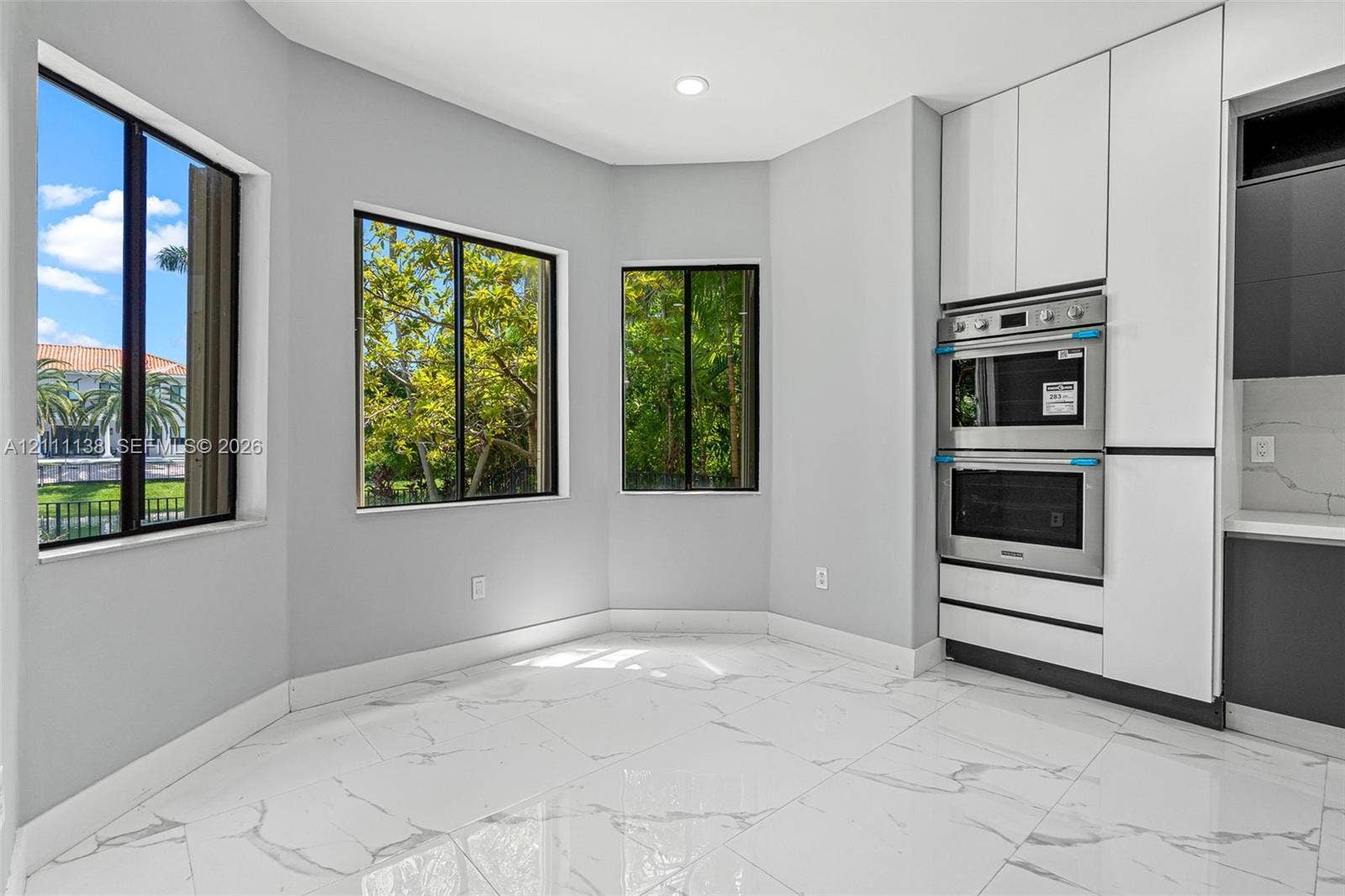 19363 SW 79th Avenue, Cutler Bay, FL 33157 Large-format tile flooring with veining, bay windows, built-in stainless steel double wall oven, and sleek floor-to-ceiling cabinetry