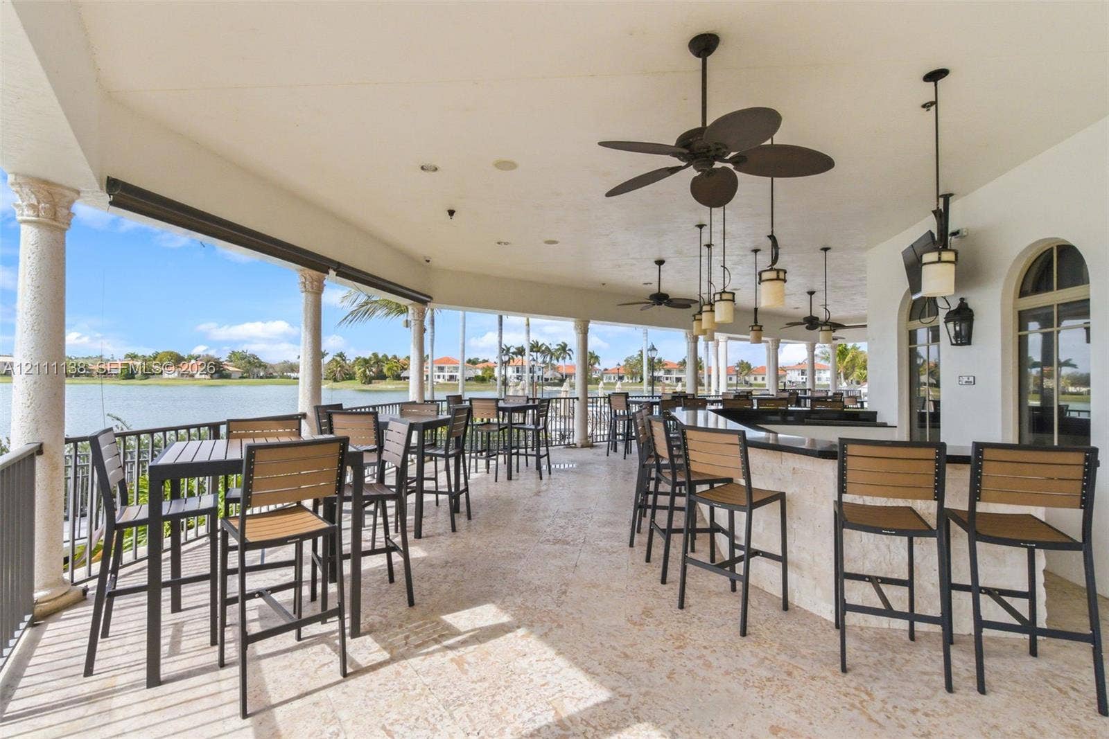 19363 SW 79th Avenue, Cutler Bay, FL 33157 Covered patio featuring stone-finish flooring, built-in stone bar with a dark countertop, ceiling-mounted fans, decorative pendant lighting, and stone columns