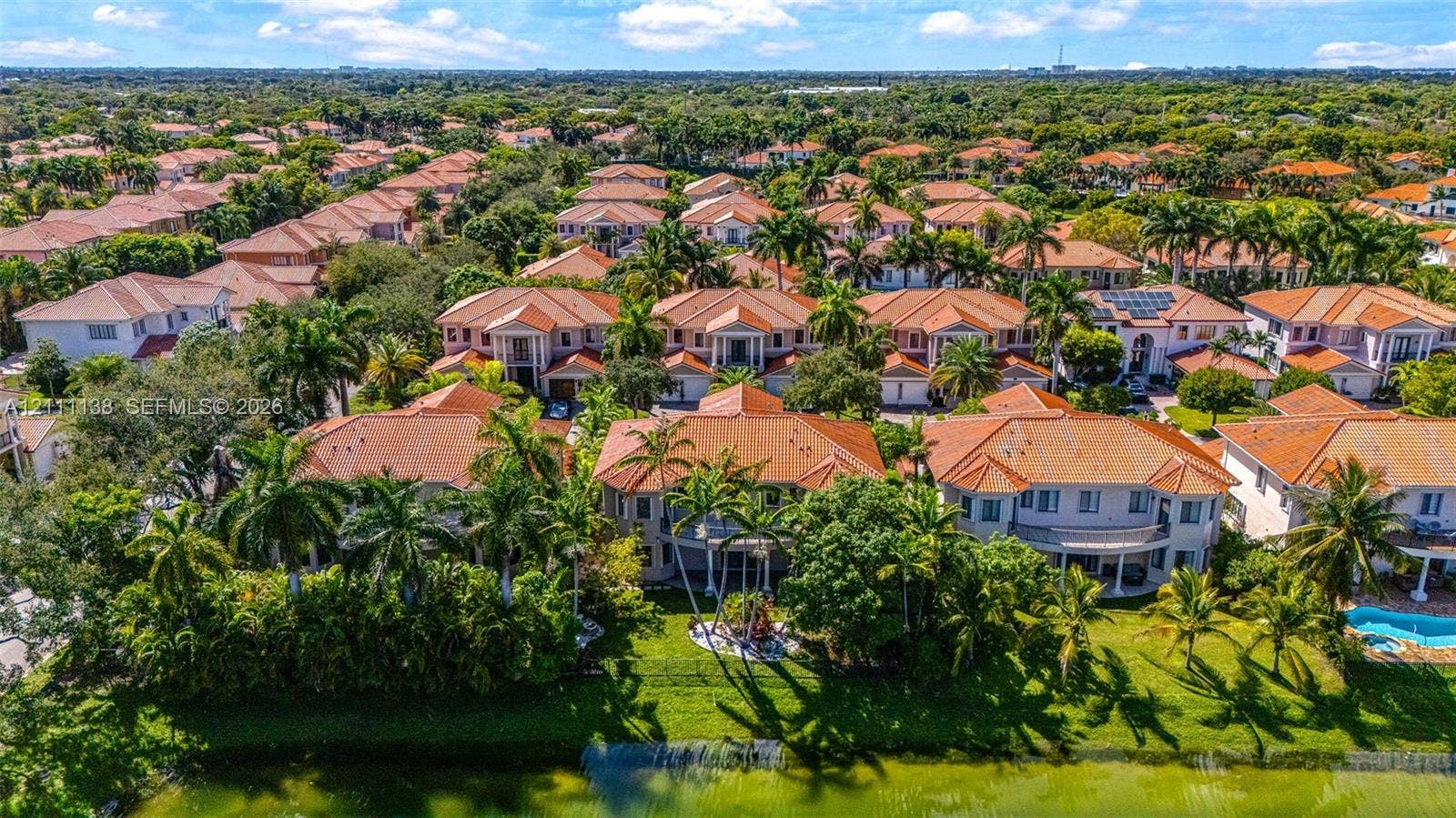 19363 SW 79th Avenue, Cutler Bay, FL 33157 Aerial perspective featuring tile-roofed residences, landscaped grounds with mature palm trees, and waterfront perimeter