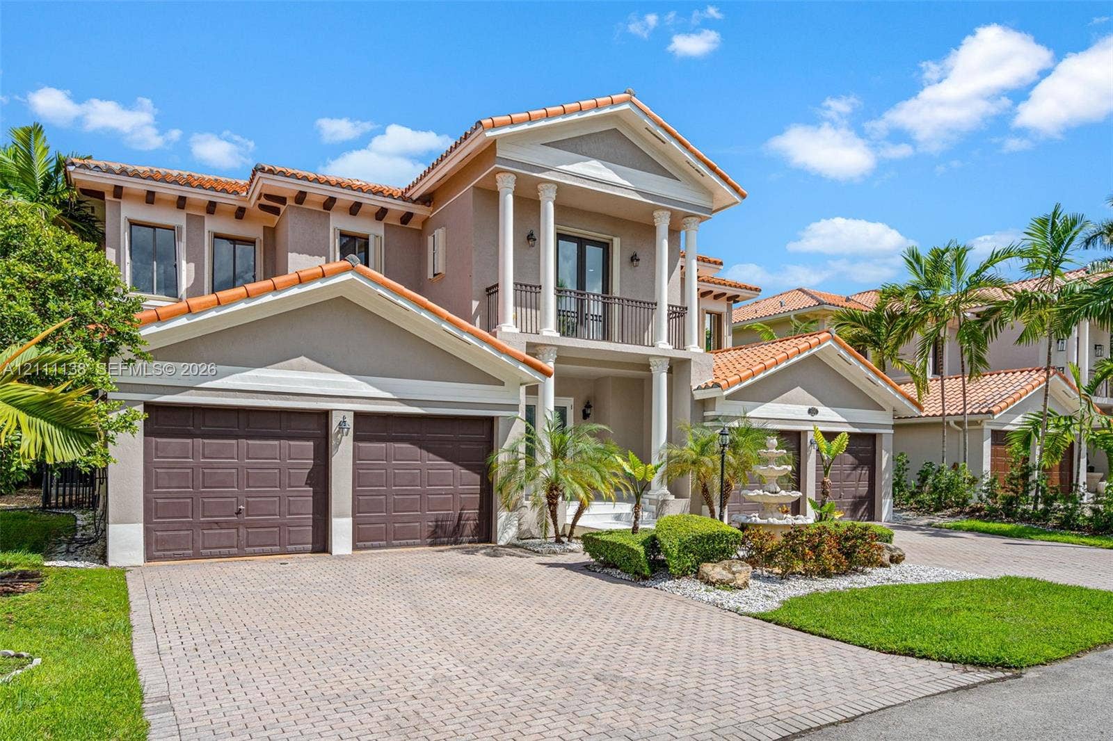19363 SW 79th Avenue, Cutler Bay, FL 33157 Two-story stucco exterior featuring a tiled roof, multi-bay garage, covered entryway with classical columns, second-level balcony, and decorative stone fountain