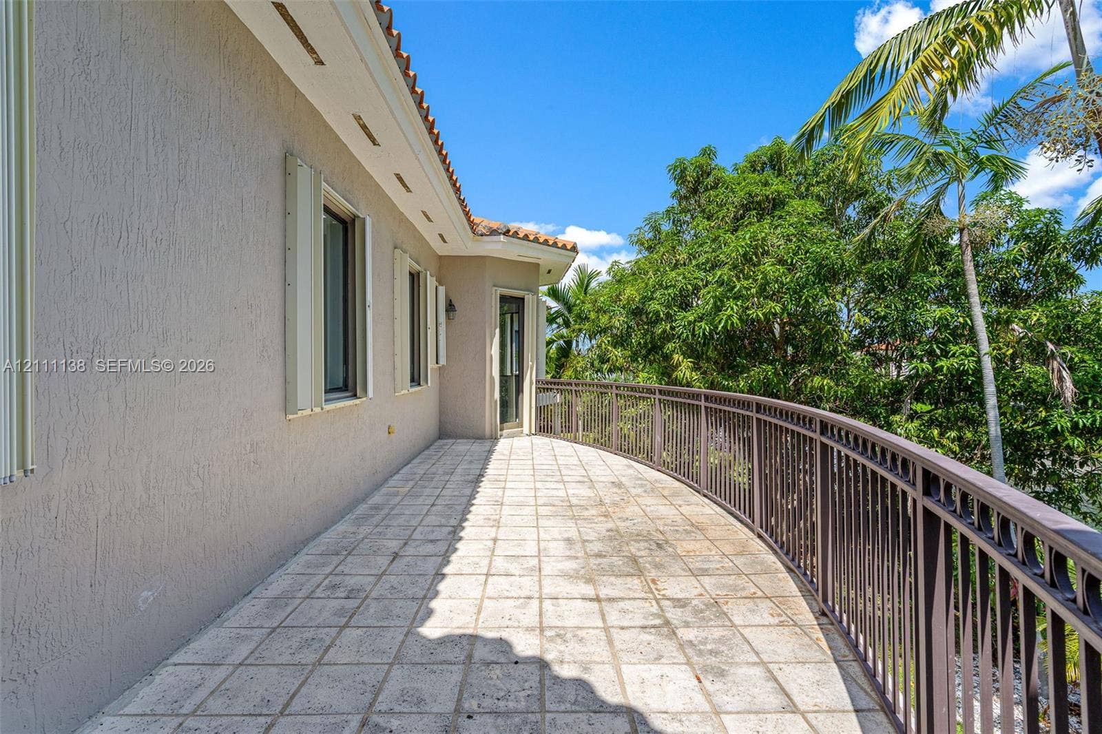 19363 SW 79th Avenue, Cutler Bay, FL 33157 Curved exterior terrace featuring stone-finish tile flooring, a metal railing, and stucco wall construction