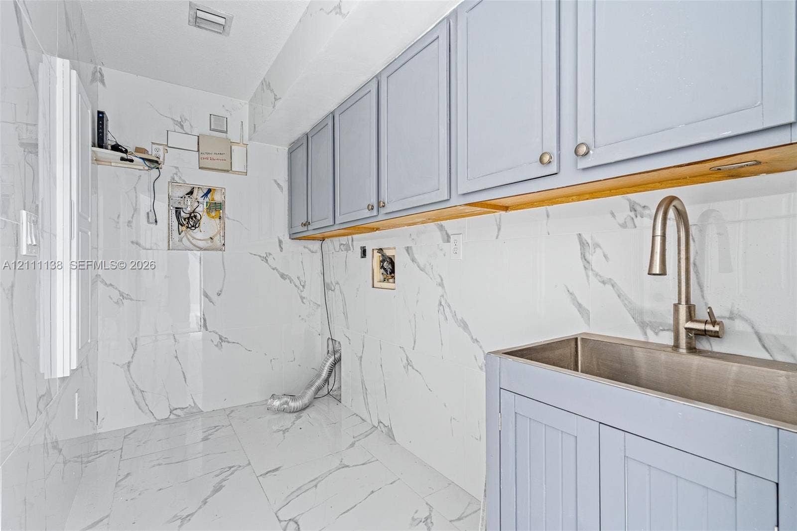 19363 SW 79th Avenue, Cutler Bay, FL 33157 Utility area featuring floor-to-ceiling large-format stone-finish wall tile, light blue shaker-style cabinetry, a stainless steel basin sink, and a gooseneck faucet