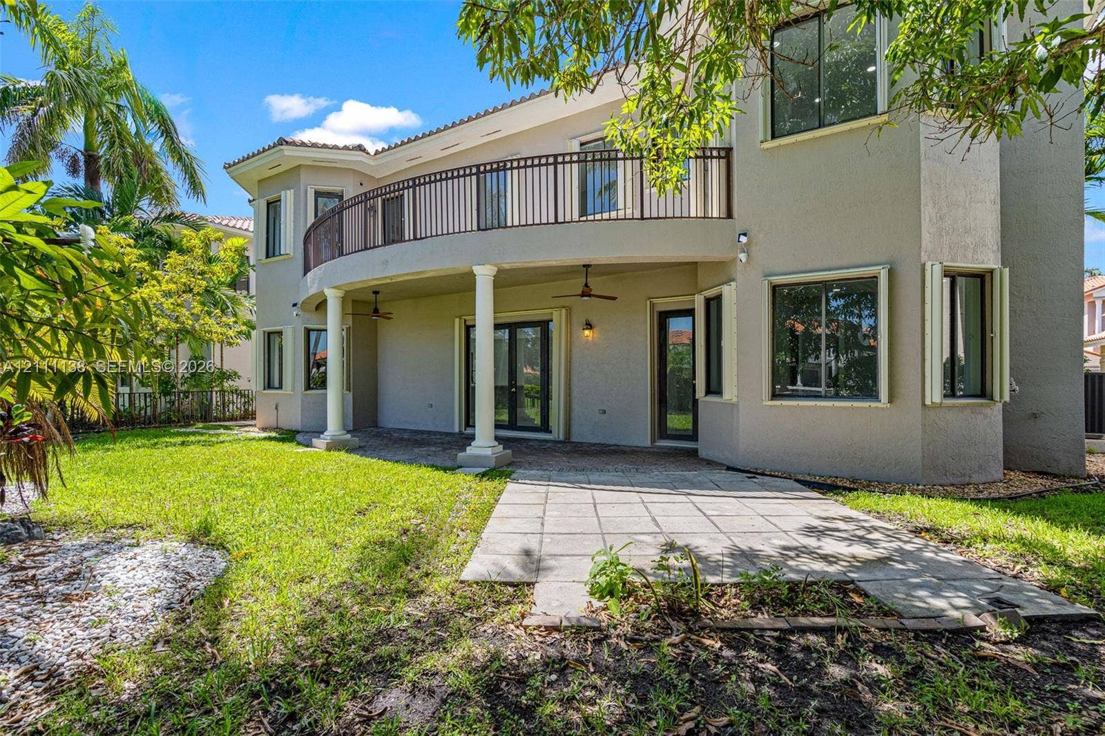 19363 SW 79th Avenue, Cutler Bay, FL 33157 Stucco exterior featuring a covered patio, paved hardscaping, a second-story curved balcony with metal railing, and structural columns