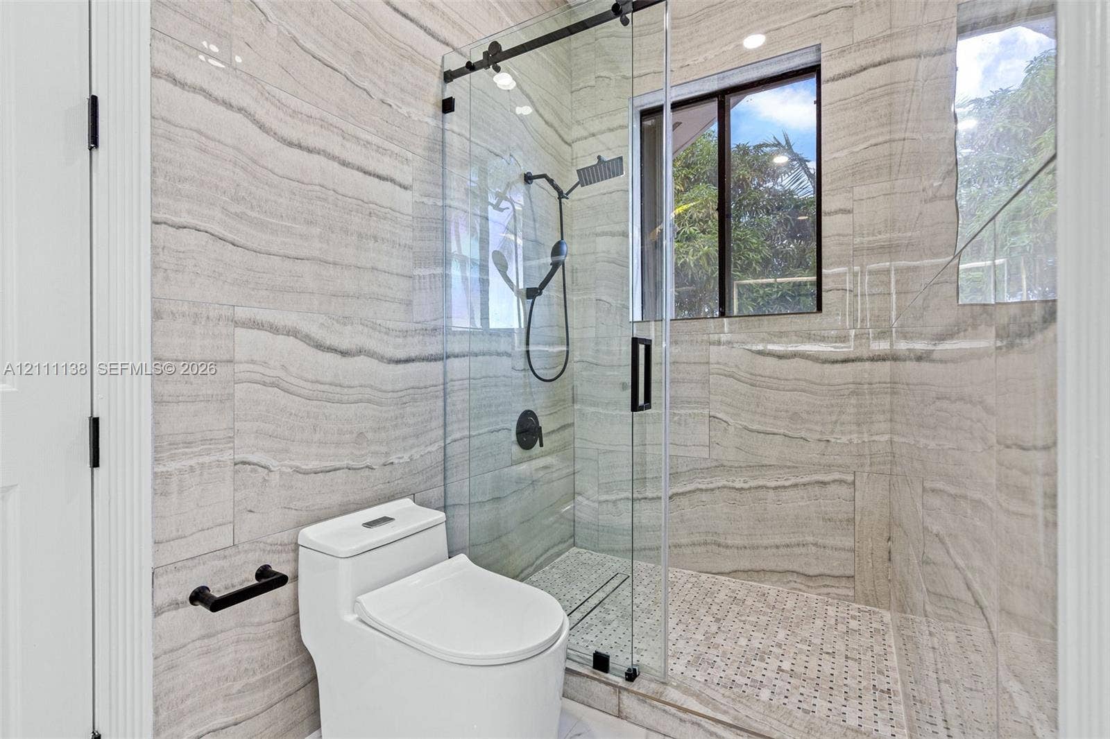 19363 SW 79th Avenue, Cutler Bay, FL 33157 Walk-in shower featuring large-format horizontal tile, glass enclosure with matte black hardware, rainfall showerhead, and mosaic tile flooring