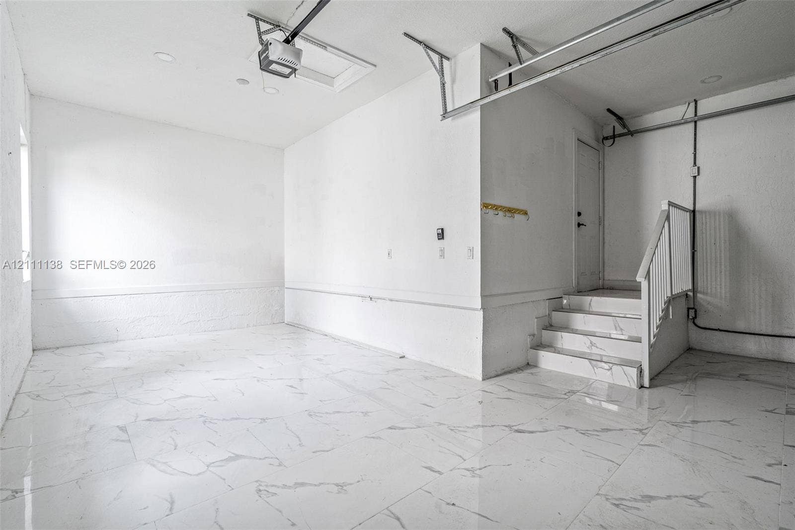 19363 SW 79th Avenue, Cutler Bay, FL 33157 Finished garage space featuring large-format tile flooring, a staircase with matching tile risers and treads, recessed lighting, and white wall finishes