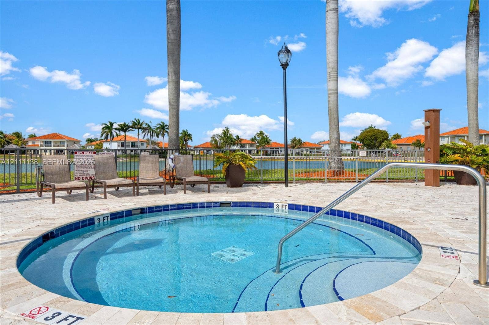19363 SW 79th Avenue, Cutler Bay, FL 33157 Circular spa featuring a stone-paver deck, built-in steps, a metal handrail, and a tile border