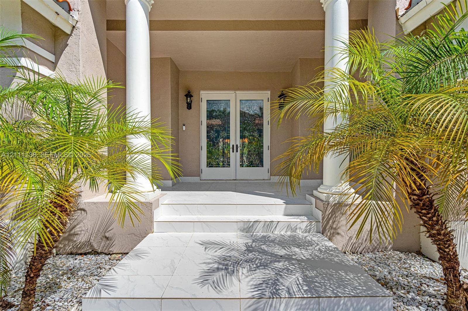 19363 SW 79th Avenue, Cutler Bay, FL 33157 Covered entryway featuring dual white columns, stone-tile steps, glass-paned double entry doors, and wall-mounted exterior lanterns