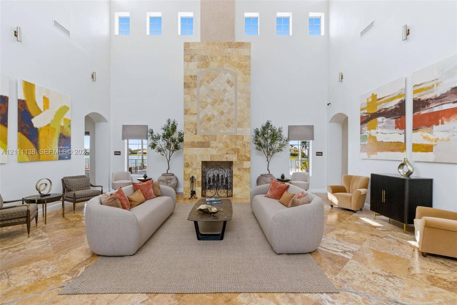 19363 SW 79th Avenue, Cutler Bay, FL 33157 Great room featuring soaring double-height ceilings, a floor-to-ceiling stone-clad fireplace, natural stone flooring, and clerestory windows