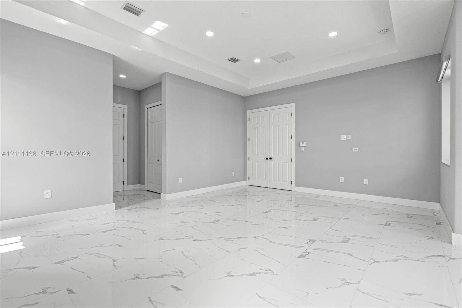 19363 SW 79th Avenue, Cutler Bay, FL 33157 Interior space featuring large-format tile flooring with marble-pattern veining, a recessed tray ceiling, recessed lighting, and double-door entry