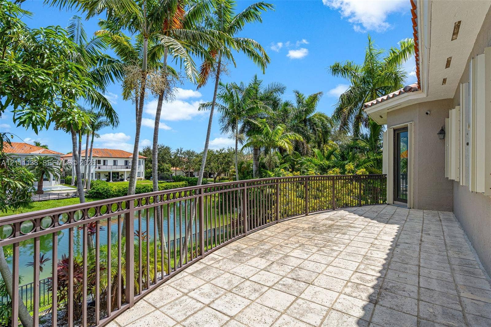 19363 SW 79th Avenue, Cutler Bay, FL 33157 Covered balcony featuring stone tile flooring, decorative metal railing, and direct water frontage