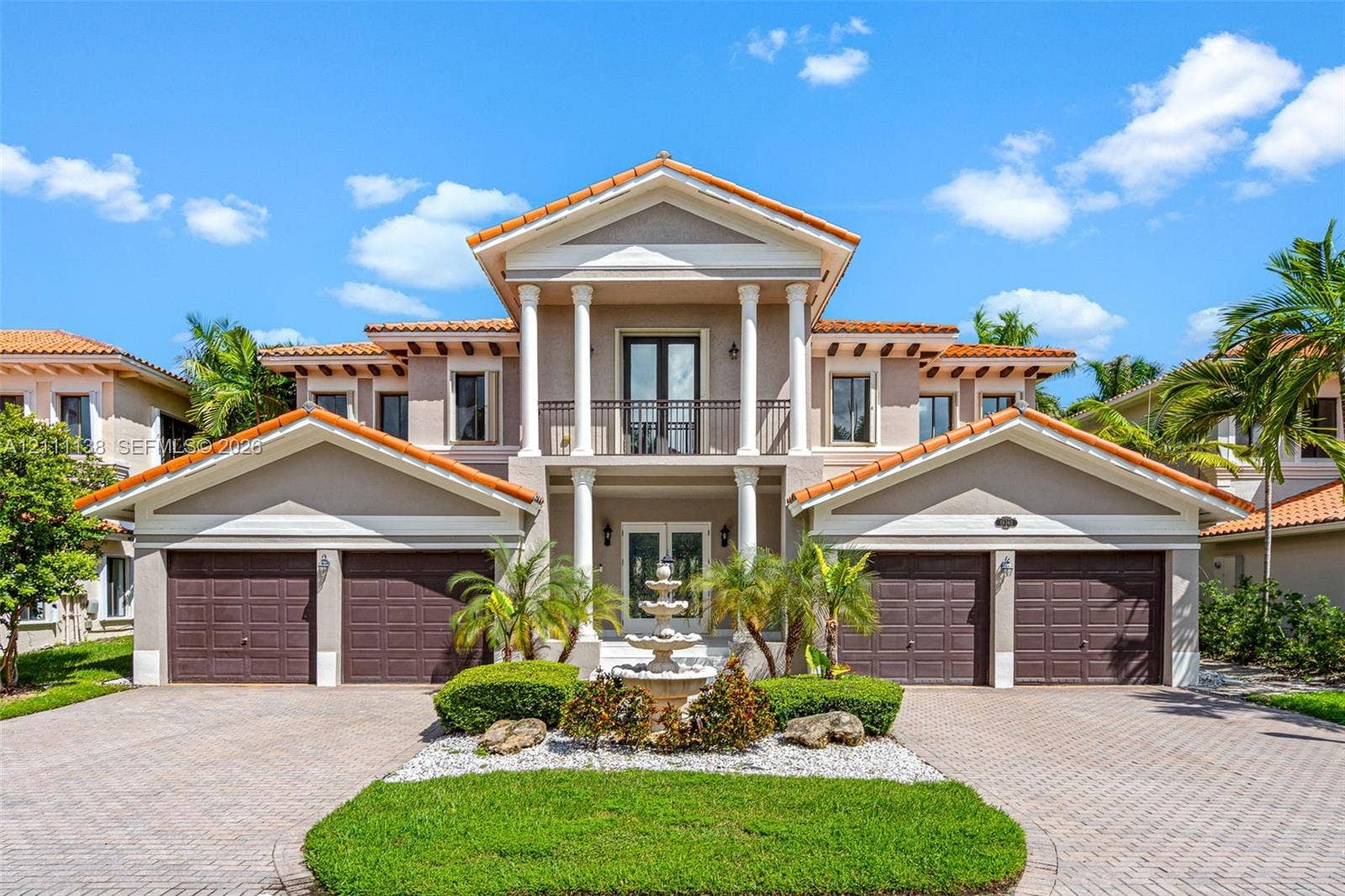 19363 SW 79th Avenue, Cutler Bay, FL 33157 Neoclassical exterior featuring a symmetrical facade, two-story columns, second-level balcony with metal railing, clay tile roof, and a central tiered stone fountain